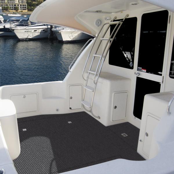 The Accept Carpet Marine is fitted into the deck floor of a motorboat. The boat is whitewash dark tinted windows and a ladder running up to the cockpit on a higher deck.