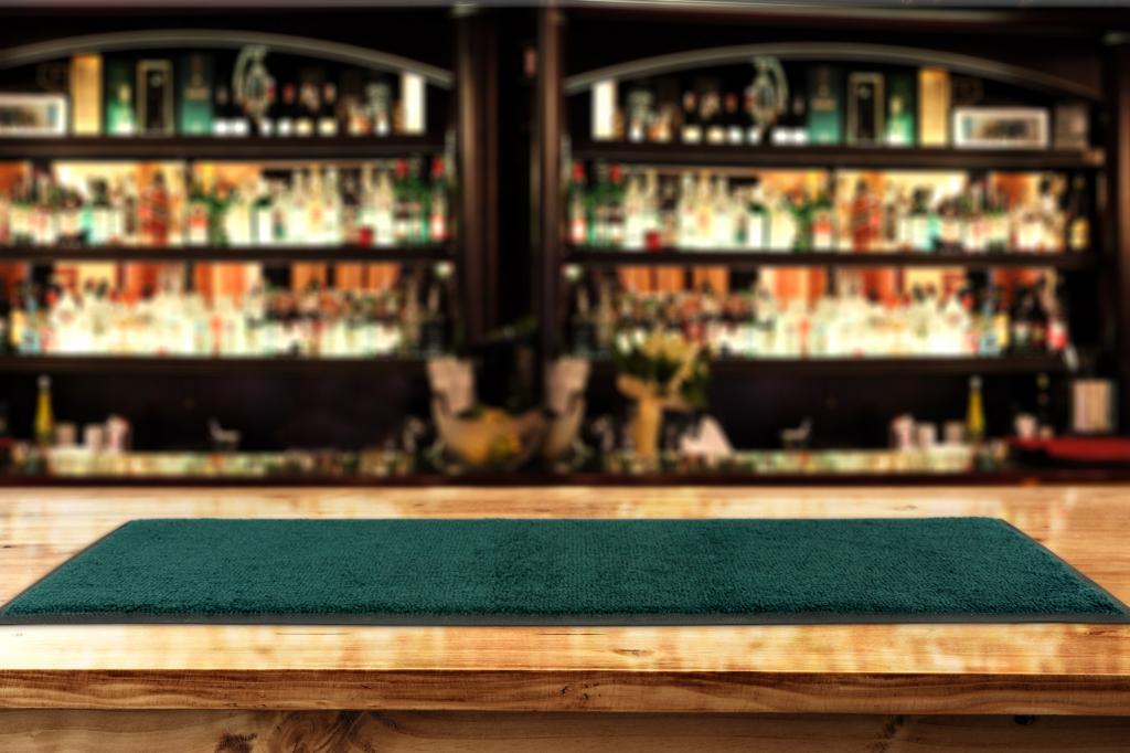 A green bar runner is laid on a bar top with an out of focus bar area behind.