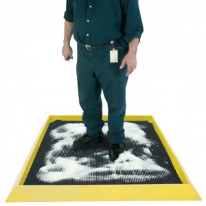 a man stands on the boot dip surrounded by soap suds for an intense clean. The boot dip mat has a black surface and a raised edge to keep the soap and water in the mat.