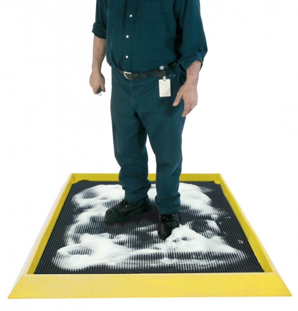a man stands on the boot dip surrounded by soap suds for an intense clean. The boot dip mat has a black surface and a raised edge to keep the soap and water in the mat.