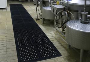 the comfort clean modular is laid in a 12x2 area of the floor. To the left of the black anti fatigue tiles are large steel drums with pipes and cables and dials.