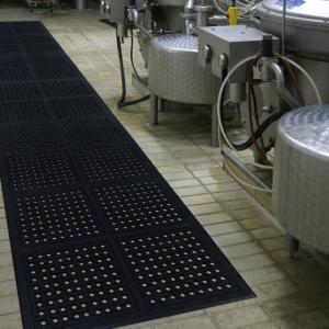 the comfort clean modular is laid in a 12x2 area of the floor. To the left of the black anti fatigue tiles are large steel drums with pipes and cables and dials.