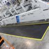 The ergo tread anti fatigue mat is laid in front of a BOBST machine. The machine is grey with dials and switches along the front. The mat is black with a yellow safety border.