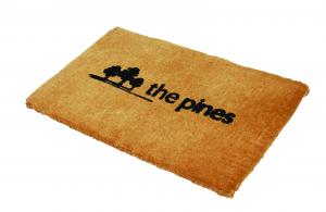 a close up of the coir logo entrance mat shows branding for The Pines