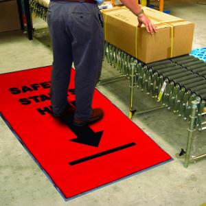 a man stands on a safety mat while seeing to a package on a conveyer belt.