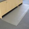 a grey anti static mat is laid on the carpeted floor in front of a wooden cupboard.