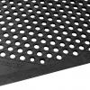A closeup of the cushion ease anti fatigue mat shows a black rubber surface with large holes for drainage.