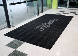 The entrance to a shopping centre is fitted with the Premium Scraper entrance mat printed with the words 'Plumpton Marketplace'