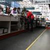 A lady serves customers at a checkout counter while standing on a black non slip, anti fatigue mat - the Super Comfort - that is fitted behind a checkout counter at Bunnings.