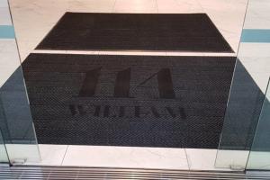 114 William Street is printed onto a black entrance mat that is fitted into a marble tiled floor.
