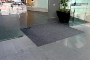 Grey Custom Entry Matting is installed in a square at Bondi Junction' entrance. It is halfway between a set of sliding glass doors.