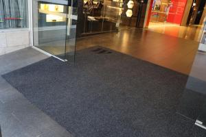 The Westfield logo is displayed on the top left corner of the Tough Scrape entrance mat. It is set halfway between sliding glass doors led up to by a ramp.
