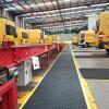 The Air Grid anti fatigue and non slip mat runs between two rows of yellow DHL vans that back onto a walkway