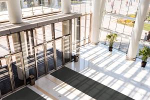 A big, light-filled entranceway with glass panels and a dark grey entrance mat - the Opti-Sorb - running down the middle.