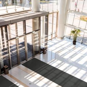 A big, light-filled entranceway with glass panels and a dark grey entrance mat - the Opti-Sorb - running down the middle.