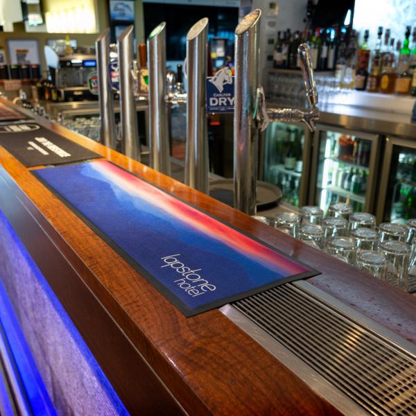 A printed bar runner with the Lapston Hotel branding is laid across a bar.