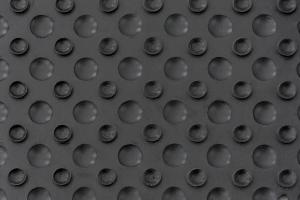 A close-up of a black rubber surface featuring a pattern of raised circular bumps and small suction-cup–like indentations, designed to provide strong grip and stability on smooth floors.